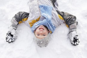 Boy Laying On Ground Making Snow Angel